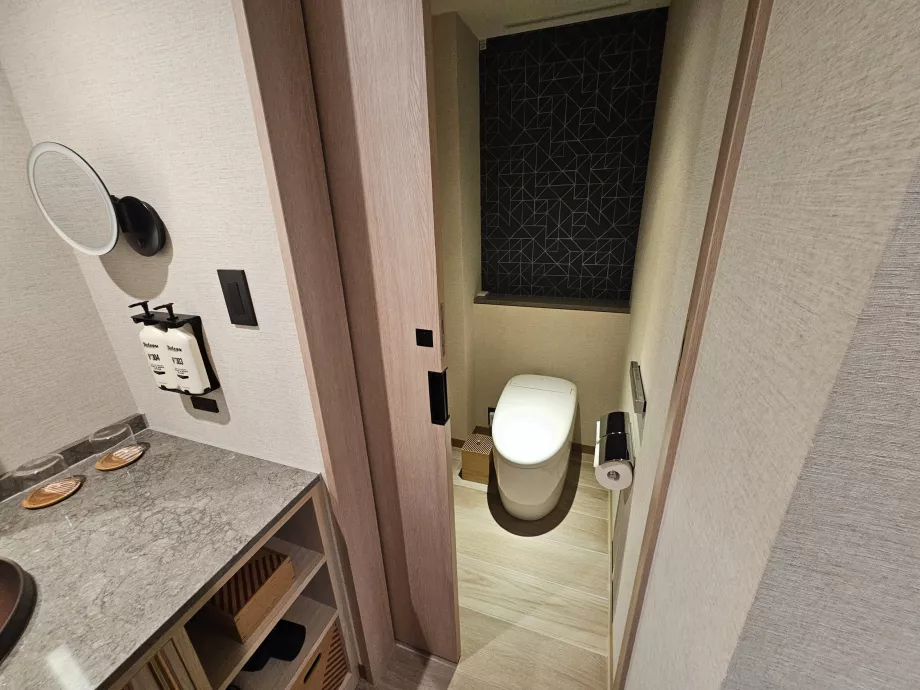 Tualetas nuo likusios vonios kambario dalies atskirtas durimis