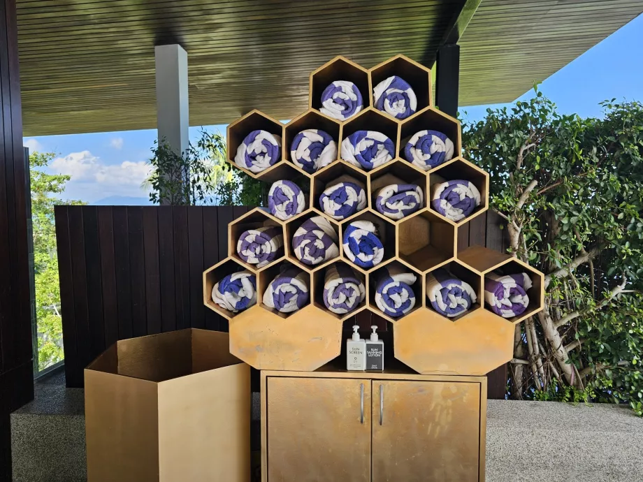 rankšluosčiai ir kremas nuo saulės prie baseino